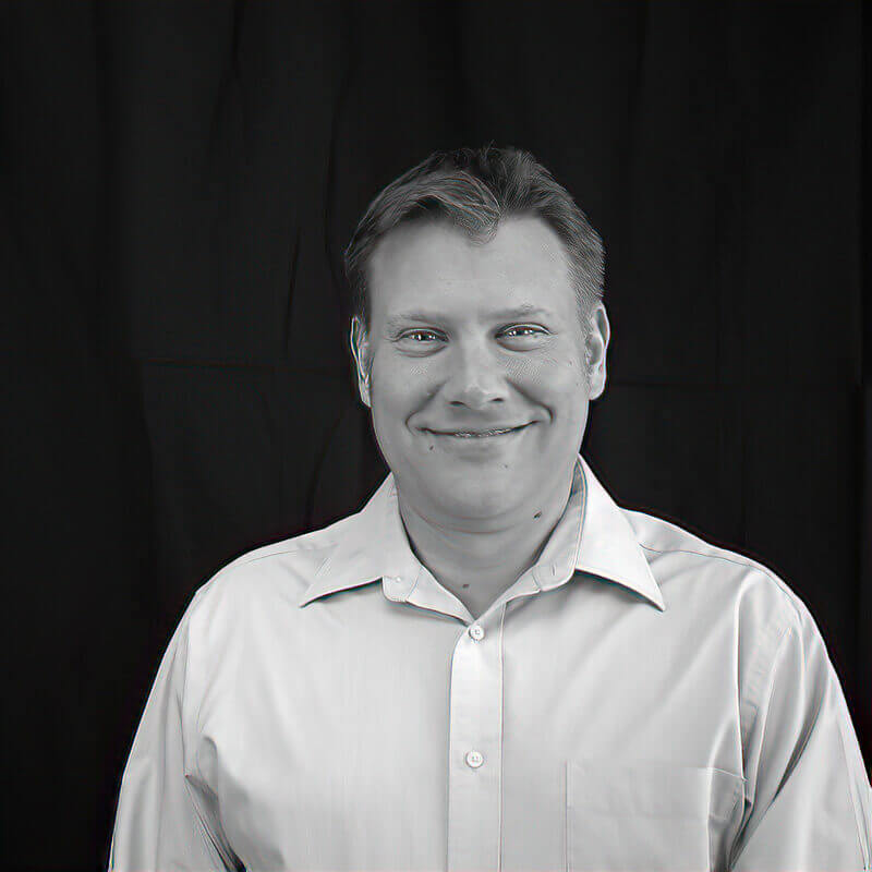 Director Kevin Pitcher smiling in front of plain background
